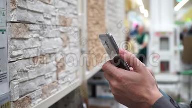 商店里有智能手机的男人挑选装修房子的材料